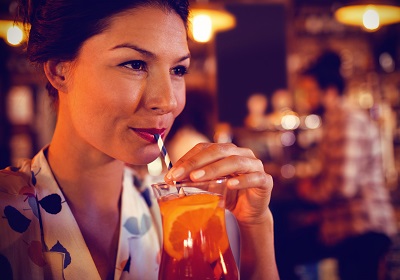 Young woman having cocktail drink in pub